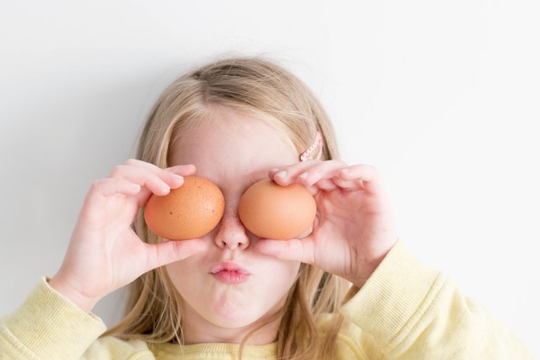Tyttö pitää kananmunia silmien edessä